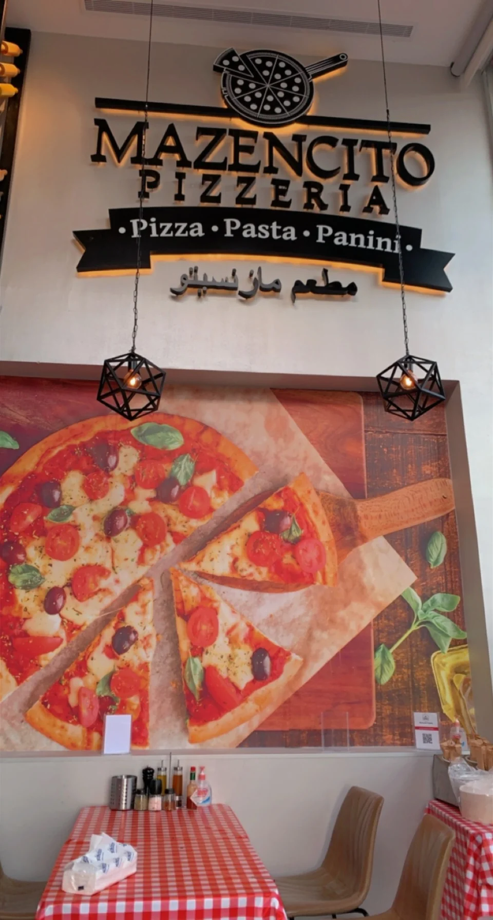 Branded pizza mural seating area with red checkered tablecloths