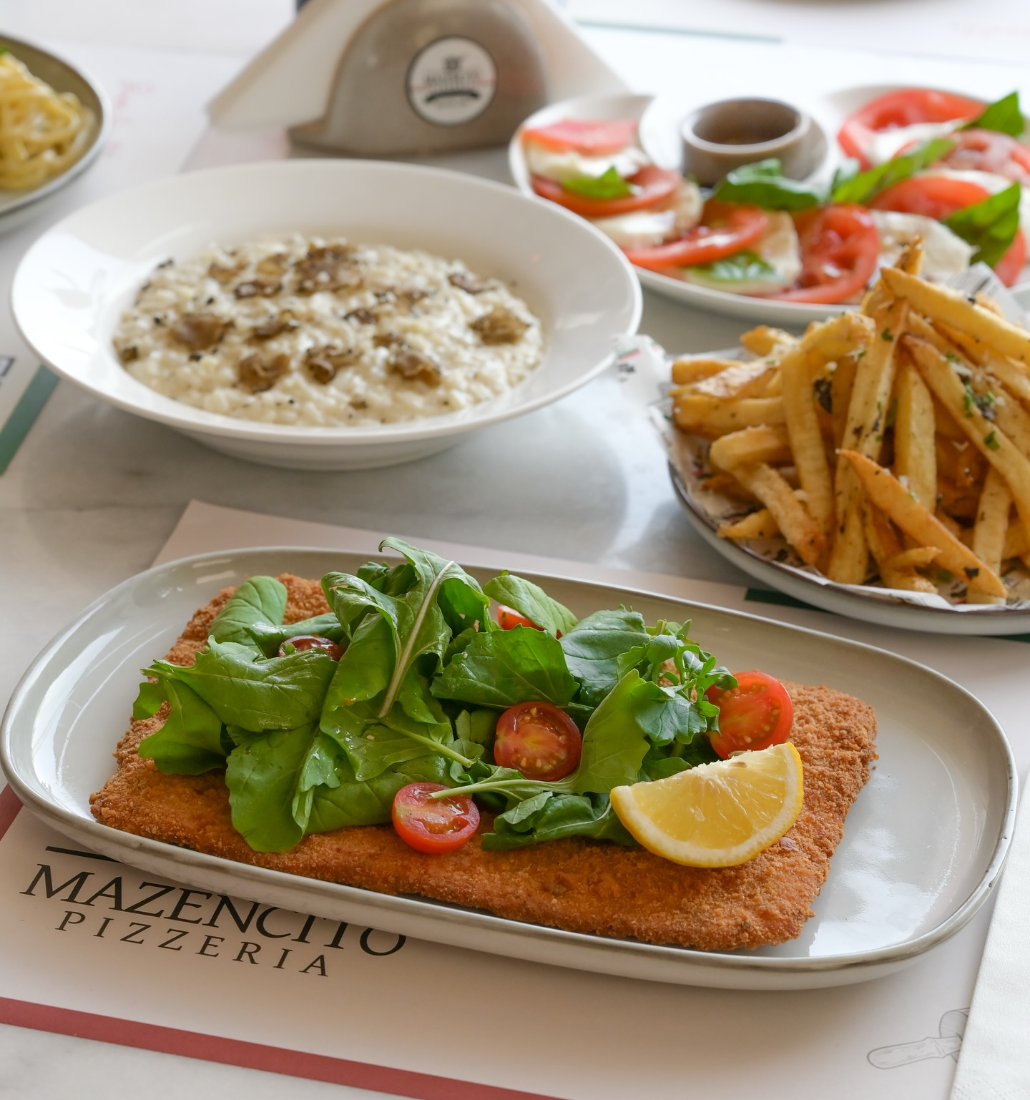 Risotto, caprese and schnitzel on the dining table at Mazencito Pizzeria