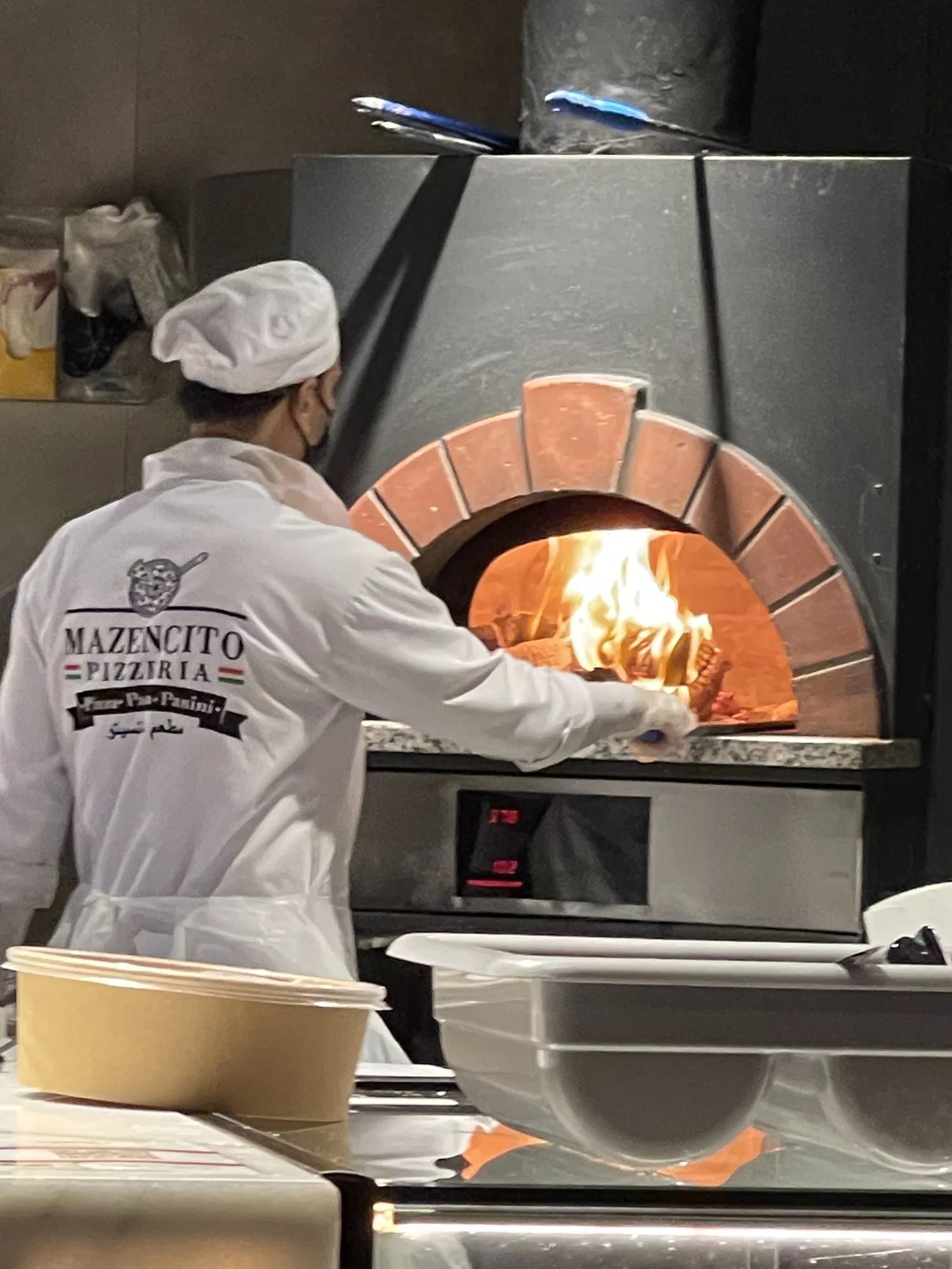 Chef sliding a pizza into the wood-fired oven