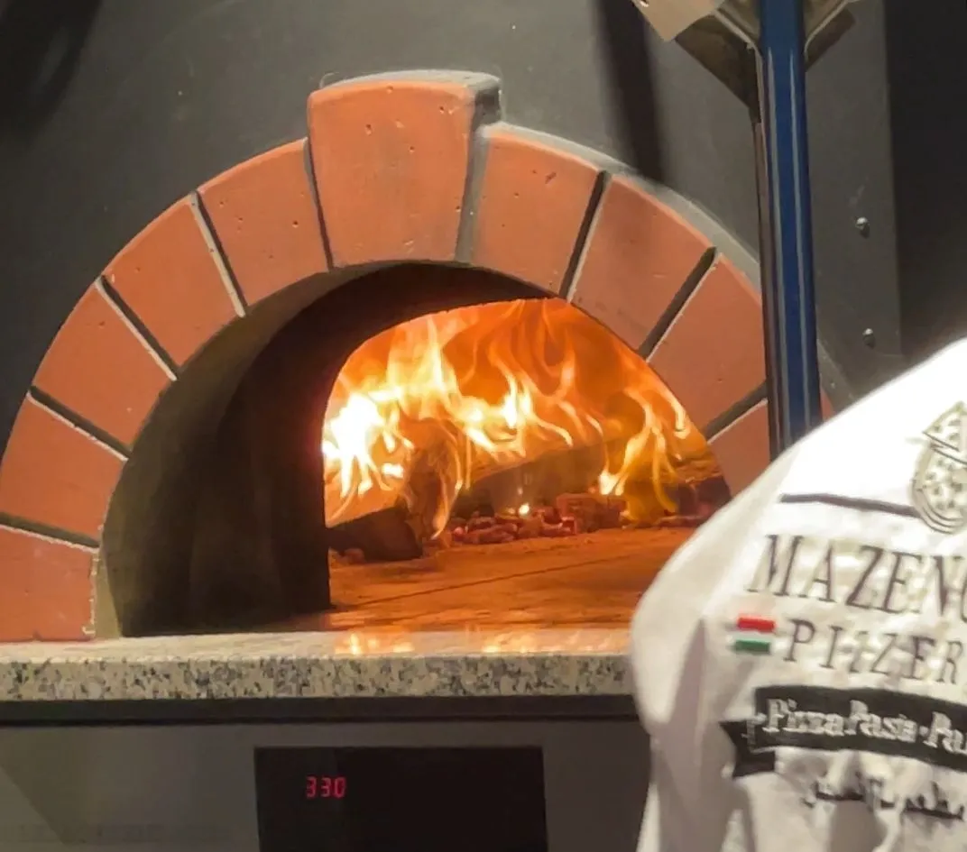 Flames inside Mazencito Pizzeria's wood-fired oven, Jeddah