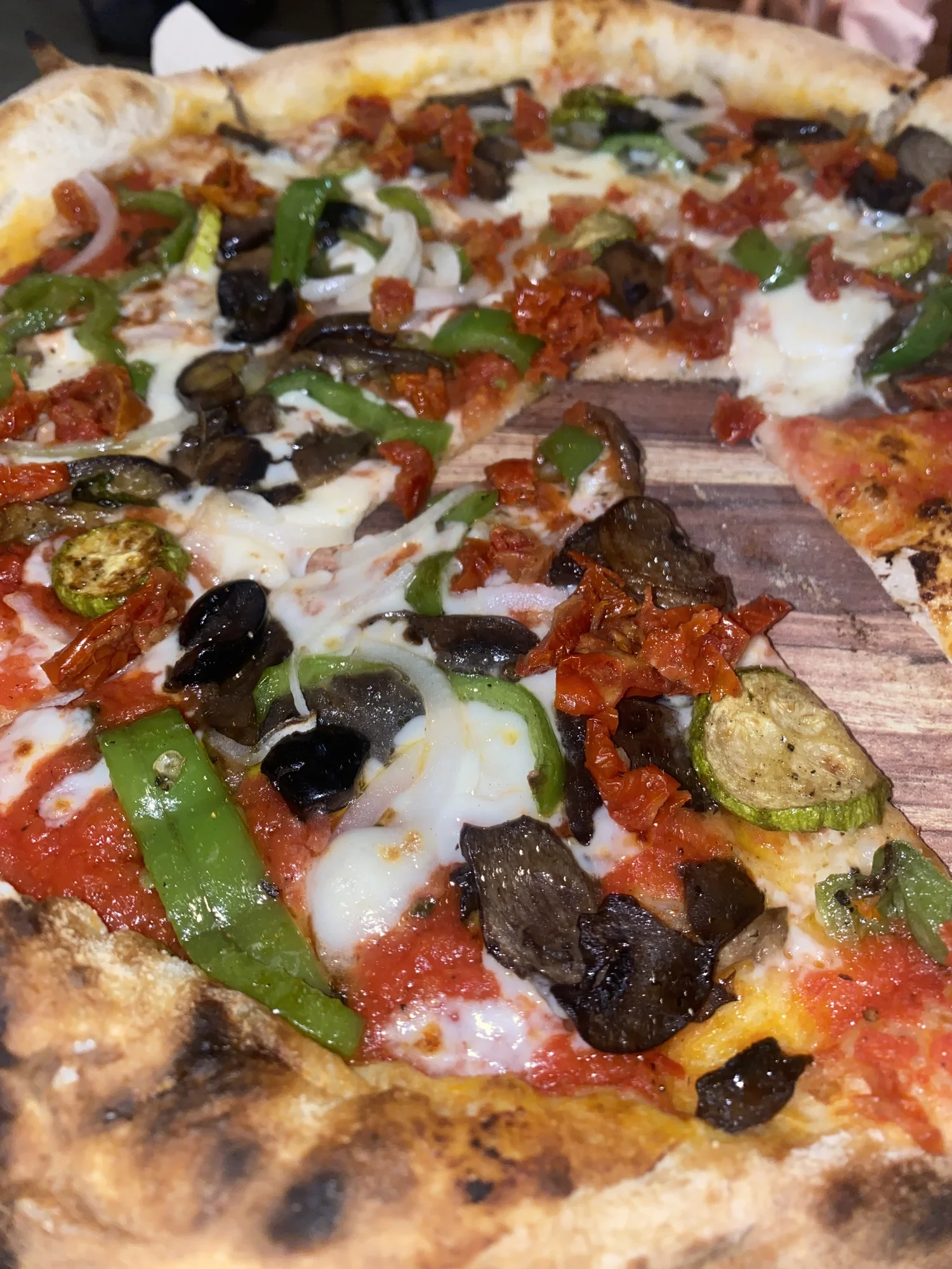 Vegetariano pizza topped with olives, sun-dried tomatoes and roasted vegetables